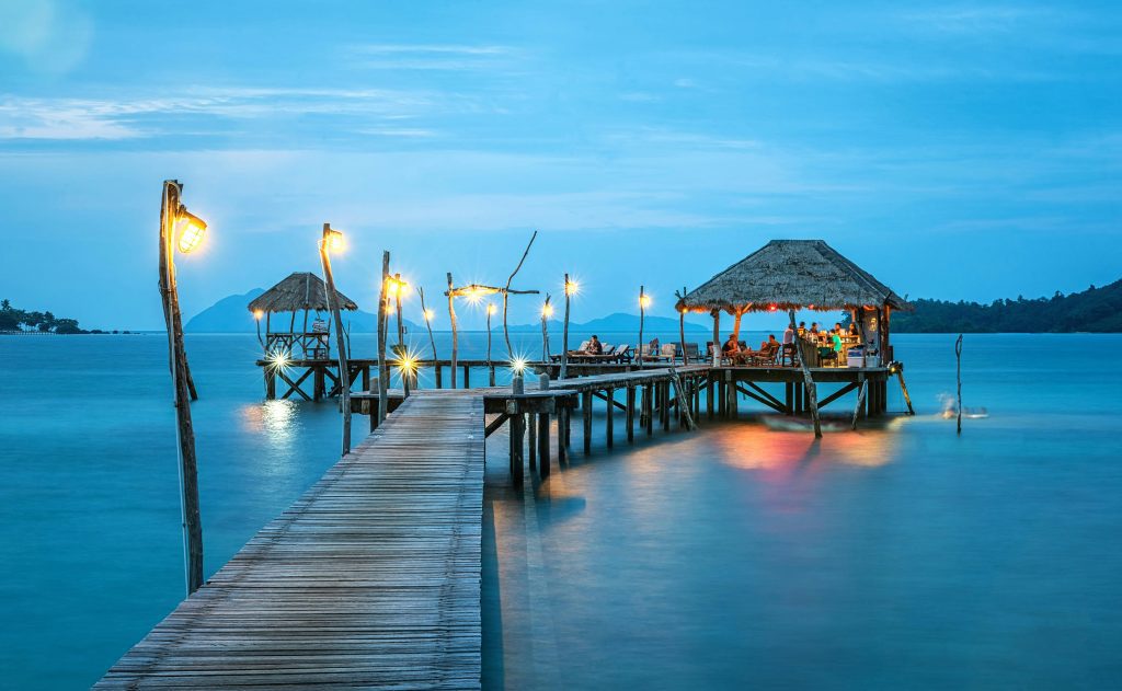 pexels-photo-237272-237272-1 Illuminated pier and bungalow on a tranquil tropical sea at twilight.