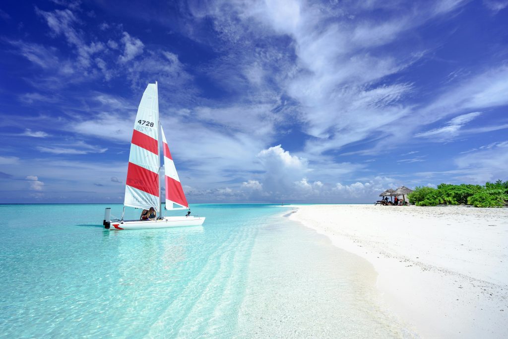 Amazing beach front Relaxing scene of a sailboat near a sandy beach in the Maldives.